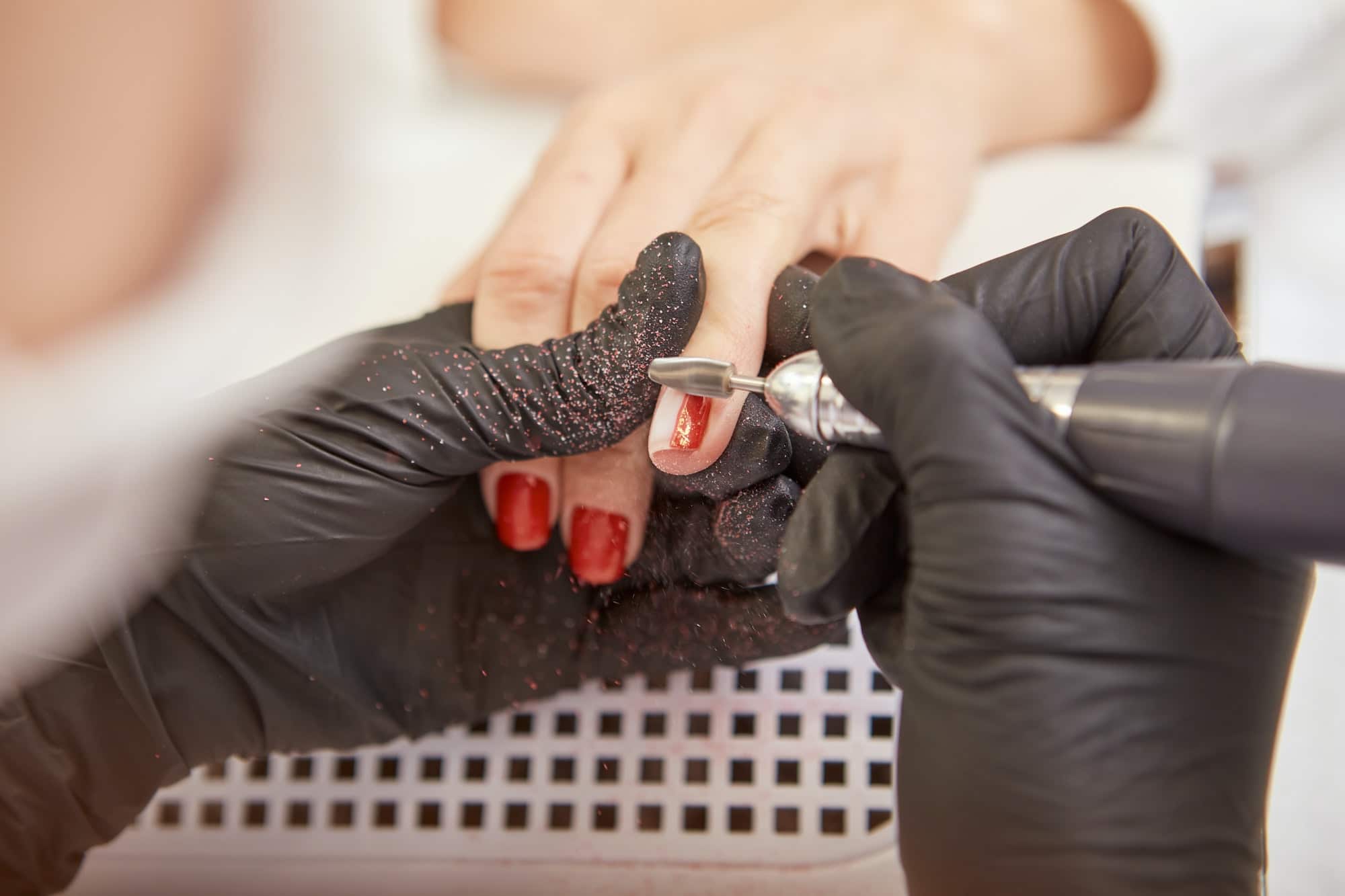 Manicurist hands in gloves removing shellac from client nails